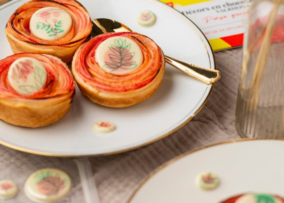 petits gateaux avec des décors en chocolat blanc avec des motifs fleuris posés dessus