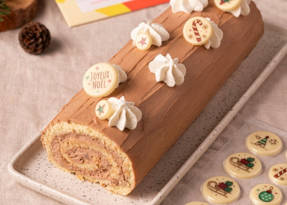 buche de noel avec au dessus des décors en chocolat blanc avec des motifs de noël