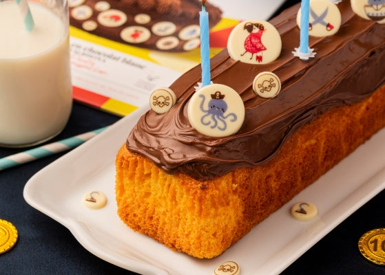 gateau enrobé de chocolat avec au dessus des décors en chocolat blanc avec des motifs pirates