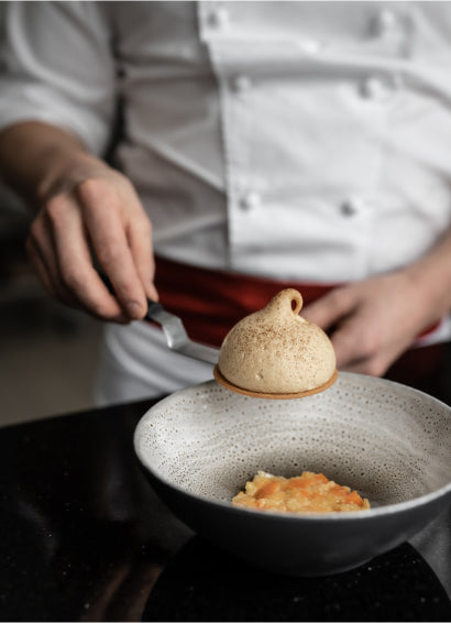 Pâtisser en train de monter un dessert à l'assiette avec du chocolat Valrhona 